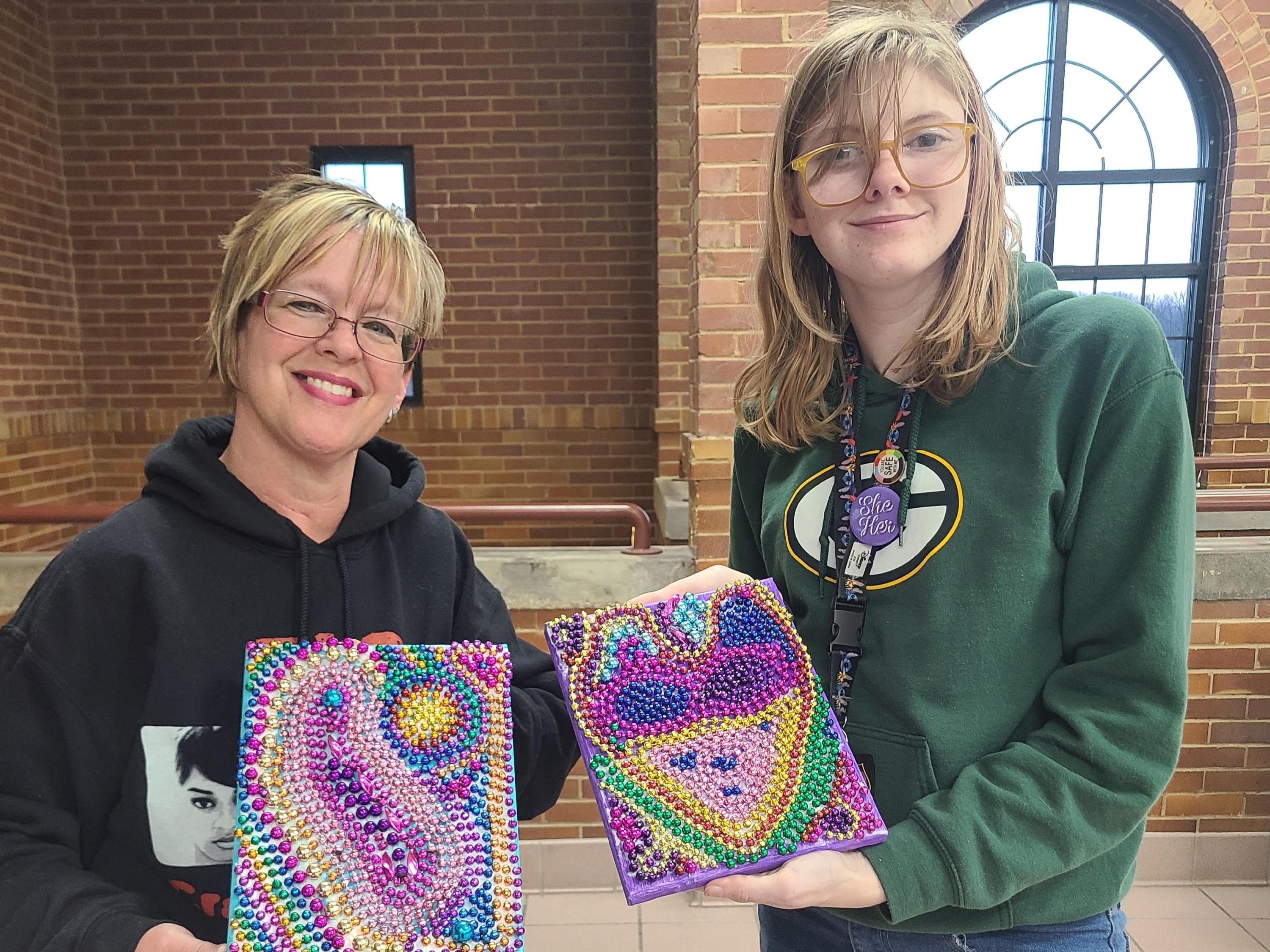 two women holding up craft projects